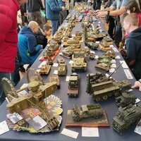Besucher betrachten zahlreiche detailreiche Fahrzeugmodelle bei einer Modellbauausstellung.