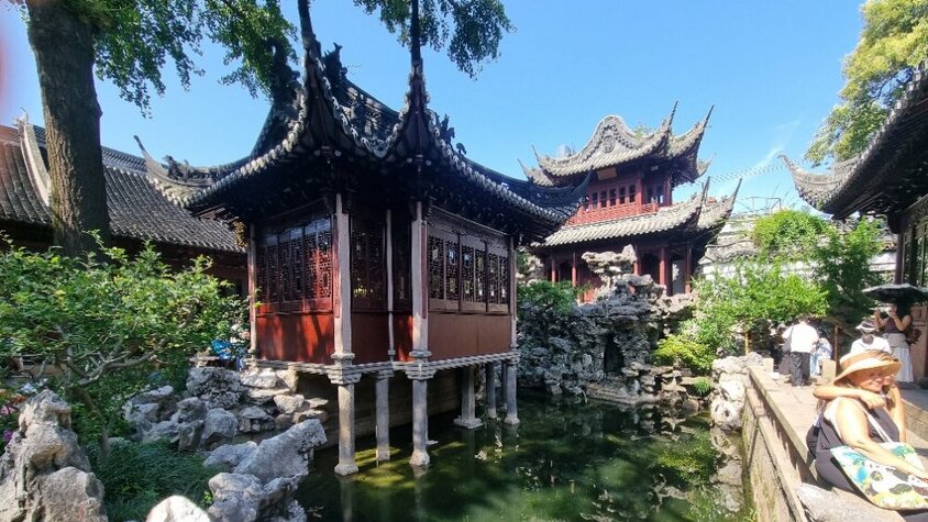 Traditionelle chinesische Pavillons mit kunstvoll geschnitzten Dächern und einem Teich im Vordergrund – Aufnahme aus Jan Wengryns Besuch im Yu-Garten in Shanghai.