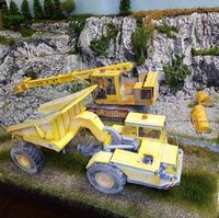 Detailreiche Modellbauszene mit gelben Baumaschinen vor einer felsigen Landschaft.