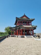 Ein traditioneller chinesischer Pavillon mit roter Holzfassade und reich verzierten Dächern vor blauem Himmel – eine Station aus Jan Wengryns Reise durch China.