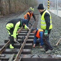 Mehrere Mitglieder eines Modelleisenbahnvereins arbeiten gemeinsam an Gleisen im Außenbereich.